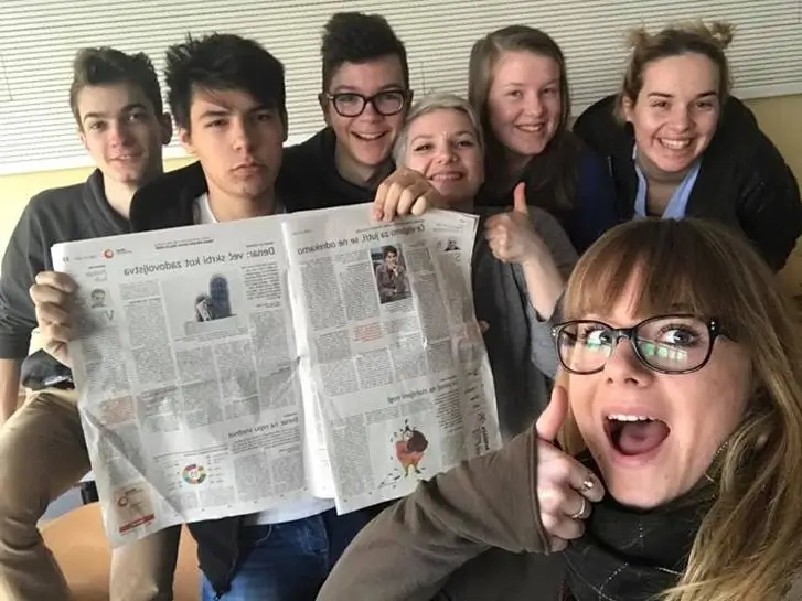 Dijaki in dijakinje nasmejani pozirajo s časopisom v roki